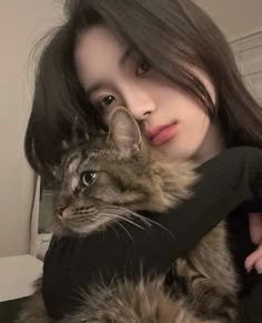 a woman holding a cat in her arms and looking at the camera with an intense look on her face