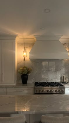 a kitchen with marble counter tops and white cabinets, along with two stools in front of the stove