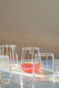 four wine glasses with different colored liquids in them