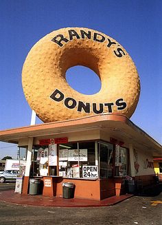 a giant doughnut sits on top of a donut shop in front of a parking lot