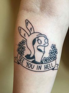 a cartoon character tattoo on the arm that says see you in hell with flowers around it