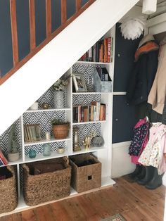 an under the stairs storage area with baskets, bookshelves and other items on shelves