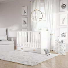 a baby's room with a white crib, chair and pictures on the wall