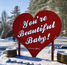 a red heart shaped sign that says you're beautiful baby on it in the snow