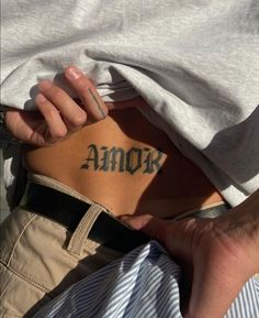 a man with a tattoo on his back that says amok in cursive writing