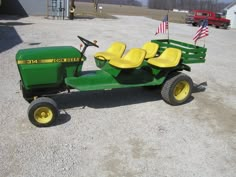 a green tractor with yellow seats sitting in the middle of a parking lot next to an american flag