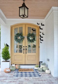 the front door is decorated with pumpkins and wreaths