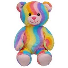 a rainbow colored teddy bear sitting up against a white background