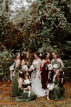 a group of women standing next to each other in front of trees and bushes with flowers on their heads