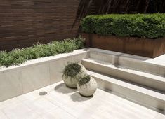 two large white vases sitting next to each other on top of a cement floor