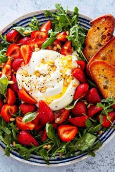 a bowl filled with strawberries and toast on top of a blue and white plate