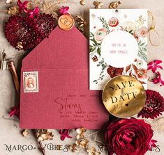 a red envelope with a gold save the date stamp on it next to some flowers