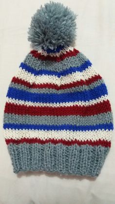 a striped knitted hat with a pom - pom on the top and bottom