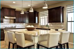 a large kitchen with marble counter tops and brown cabinets, along with white bar stools