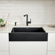 a black kitchen sink sitting under a faucet next to a white counter top