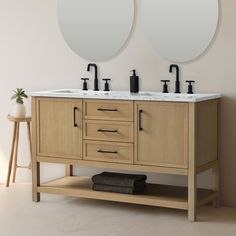 two round mirrors are on the wall above a double sink vanity with black faucets