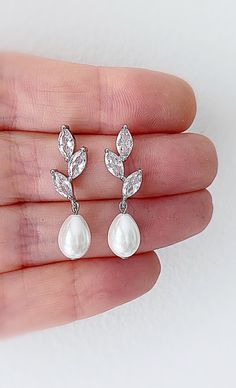 Our pearl drop bridal earrings are simply stunning!  A simple classic earring. Little bit of bling, classic pearl, small drop... perfect combo!  These dainty pearl drop earrings catch the light, packing serious sparkle for their size. Combining marquise crystals stones in a modern leaf design they're finished with glowing Swarovski pearls. With just the right amount of sparkle, this dainty pair is perfect for brides, mother of the bride and bridesmaids alike. Available in silver or gold to suit all skin tones.  -Drop Pearls are light ivory- These Crystal and pearl wedding earrings will add a flawless finish to every bridal look. Gorgeous Coordinating crystal Leaf Hair comb  and Necklace set also available. SHOP MORE STYLES  https://www.etsy.com/ie/shop/BridalStar?ref=related&listing_id=768 Dainty Sterling Silver Teardrop Earrings For Wedding, Delicate Silver Teardrop Earrings For Wedding, Silver Bridal Earrings With Pearl Charm For Wedding, White Gold Drop Pearl Earrings For Wedding, Dainty Sterling Silver Pearl Earrings For Wedding, Elegant Metal Bridal Earrings With Pearl Drop, Silver Drop Bridal Earrings With Pearl Charm, Silver Pearl Drop Earrings For Bridal Shower, Wedding Pearl Drop Earrings In Sterling Silver