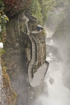 the stairs are built into the side of the cliff by the water and fog in the air