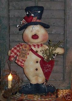 a snowman with a hat and scarf on top of a table next to a candle