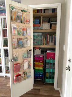 the door is open and there are many bookshelves in the room that have bins on them