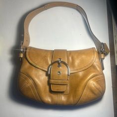 This Is An Authentic Vintage Coach Shoulder Handbag Purse Made Of High-Quality Leather In A Beautiful Brown Color. It Features A Solid Pattern And A Button And Buckle Closure. The Bag Is 11 Inches Wide, 6.7 Inches (17 Cm) High, And 2.4 Inches (6 Cm) Deep, With A Length Of 9.8 Inches (25 Cm). The Strap Drop Ranges From 6.3 To 8.7 Inches (16 To 22 Cm) And Is Made Of Stainless Steel And Leather. The Bag Also Comes With A Coach Charm Accessory. The Interior Lining Is Made Of Brown Fabric, And The Ha Classic Gold Satchel With Branded Hardware, Vintage Shoulder Bag With Silver-tone Hardware And Double Handle, Vintage Double Handle Shoulder Bag With Silver-tone Hardware, Everyday Vintage Shoulder Bag With Branded Hardware, Gold Leather Bags With Branded Hardware, Classic Gold Shoulder Bag With Silver-tone Hardware, Designer Gold Soft Leather Bag, Vintage Leather Shoulder Bag With Branded Hardware, Coach Leather Shoulder Bag With Handles