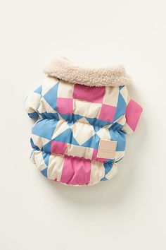 a blue and pink checkered dog coat on a white surface with a brown tag