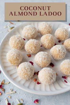 a white plate topped with coconut balls covered in powdered sugar and rose petals on a blue surface