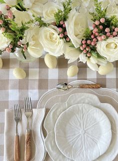 the table is set with white flowers and place settings for an easter dinner or brunch