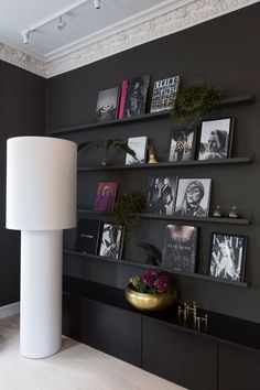 a living room with black walls and pictures on the wall, including a white lamp