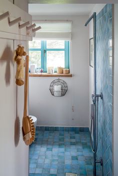 a bathroom with blue tiles and wooden utensils hanging from the wall next to the shower