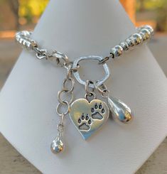 a silver bracelet with a dog paw and heart charm