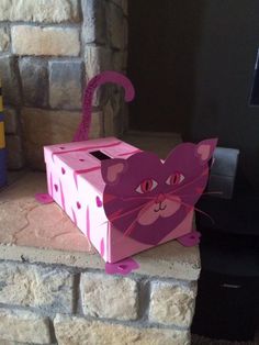 a pink cat box sitting on top of a brick wall