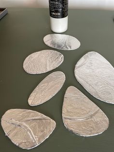 four pieces of tinfoil sitting on top of a table next to a bottle of glue