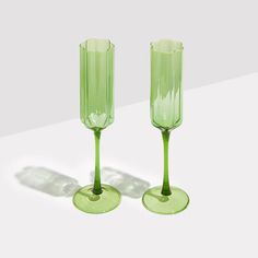 two green wine goblets sitting on top of each other in front of a white background