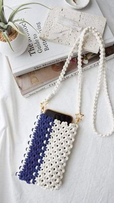 a white and blue purse sitting on top of a table next to a stack of books