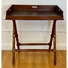 a wooden tray with handles on it sitting on top of a hard wood floor next to a white wall