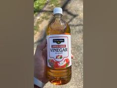 a person holding a bottle of vinegar in their hand