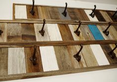 a wooden wall hanging with metal hooks on it