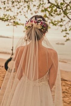 the back of a bride's wedding dress with flowers in her hair and veil