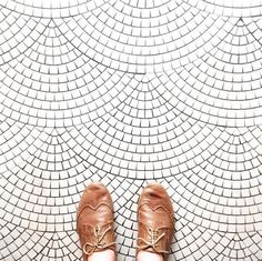 someone's feet in brown shoes standing on a tile floor