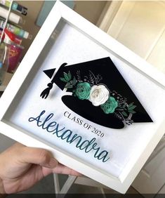 a hand holding up a graduation cap with flowers on it