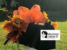 a mailbox decorated with sunflowers and orange mesh bow sits in the grass