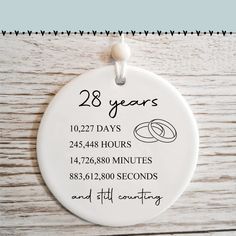 a white ceramic ornament with the date and wedding rings on it for 28 years