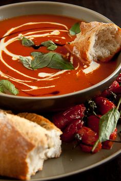 a bowl of soup with bread on the side and other food items in front of it