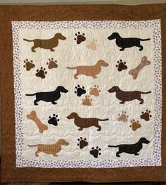 a quilted wall hanging with dogs on it's sides and paw prints in the middle