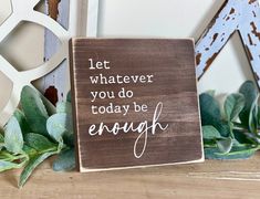 a wooden sign that says let whatever you do today be enough next to some plants