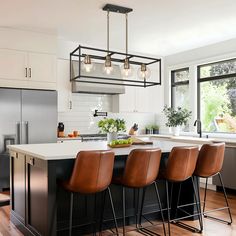 a kitchen island with four stools in front of it and an island that has three chairs