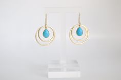 The Gold Double Circle Turquoise Earrings are exquisite jewelry pieces showcasing a pair of interconnected circular charms crafted from gleaming gold. Accented with vibrant turquoise stones, these earrings effortlessly combine a sense of timeless beauty with a pop of color. Turquoise Earrings Gold, Phone Items, Turquoise Stones, Exquisite Jewelry, The Gold, Turquoise Earrings, Tennis Bracelet, Turquoise Stone, Timeless Beauty