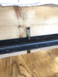 a close up of a metal rail on a wooden floor with wood planks behind it