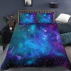 a bed covered in purple and blue galaxy comforter sets with pillows on top of it